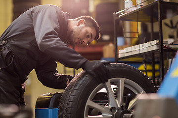 Image showing auto mechanic balancing car wheel at workshop