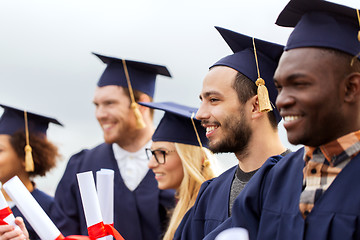 Image showing happy students in mortar boards with diplomas