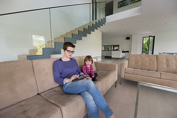 Image showing mother and her cute little daughter are using a tablet