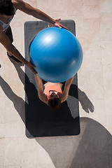 Image showing woman and personal trainer doing exercise with pilates ball