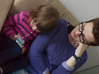 Image showing mother and her cute little daughter are using a mobile phone