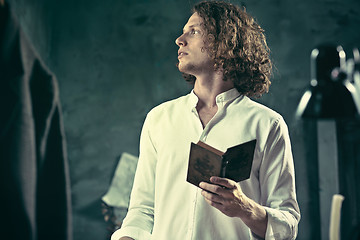 Image showing Writer at work. Handsome young writer standing near the table and making up something in his mind