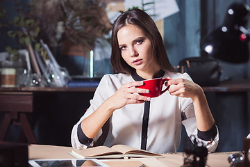 Image showing Young beautiful woman working with cup of coffee