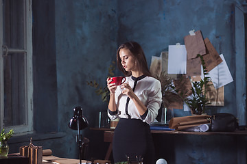 Image showing Young beautiful woman working with cup of coffee