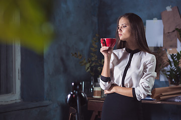 Image showing Young beautiful woman working with cup of coffee