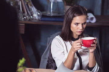 Image showing Young beautiful woman working with cup of coffee