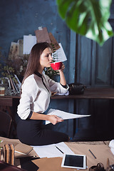 Image showing Young beautiful woman working with cup of coffee