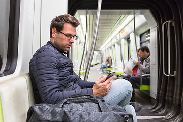 Image showing Male commuter reading from mobile phone screen in metro.