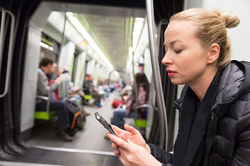 Image showing Young girl reading from mobile phone screen in metro.