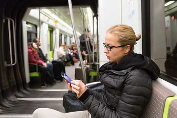 Image showing Young girl reading from mobile phone screen in metro.