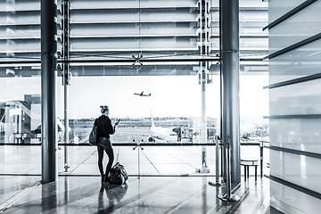 Image showing Young woman waiting at airport, looking through the gate window.