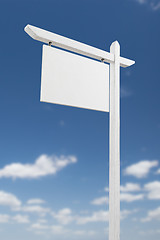 Image showing Blank Real Estate Sign Over A Blue Sky with Clouds.