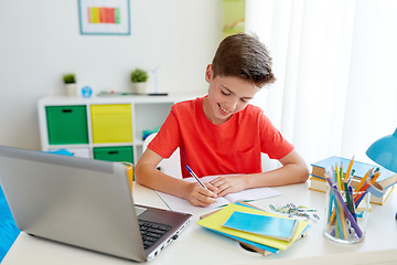 Image showing student boy with laptop writing to notebook