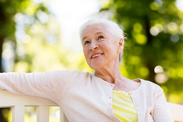 Image showing happy senior woman sitting on bench at summer park