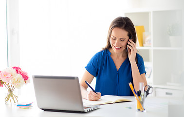 Image showing woman with notepad calling on smartphone at office