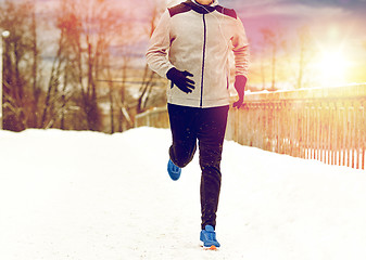 Image showing man in earphones running along winter bridge