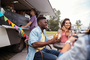 Image showing happy friends with drinks eating at food truck