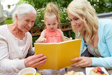 Image showing happy family reading book at cafe terrace