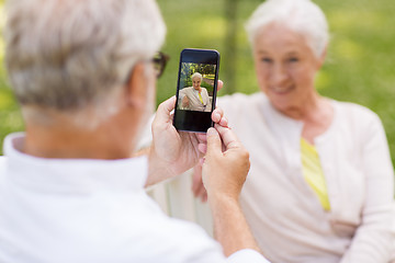 Image showing old woman photographing man by smartphone in park