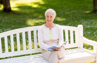 Image showing happy senior woman reading book at summer park