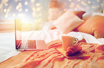 Image showing laptop, coffee and croissant on bed at cozy home