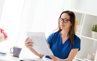 Image showing businesswoman reading newspaper at office