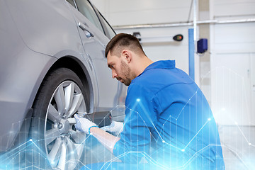 Image showing mechanic with screwdriver changing car tire