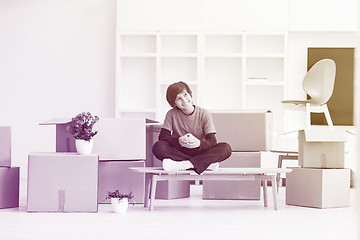 Image showing boy sitting on the table with cardboard boxes around him