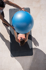 Image showing woman and personal trainer doing exercise with pilates ball