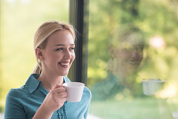 Image showing young woman drinking morning coffee by the window