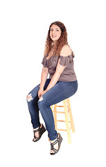 Image showing Young woman sitting on a bar chair, smiling