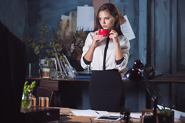 Image showing Young beautiful woman working with cup of coffee