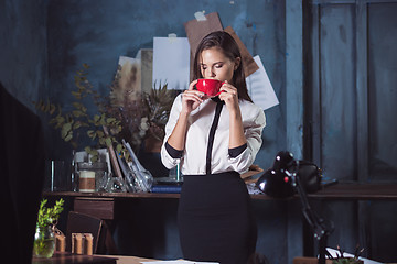 Image showing Young beautiful woman working with cup of coffee