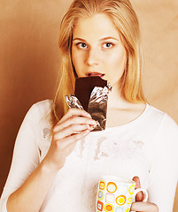 Image showing young cute blond girl eating chocolate and drinking coffee close