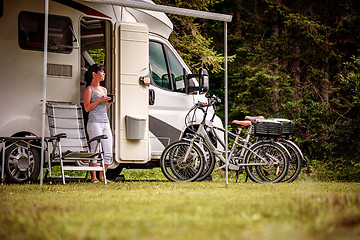 Image showing Woman is standing with a mug of coffee near the camper RV.