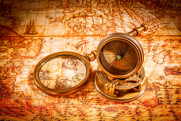 Image showing Vintage compass lies on an ancient world map.