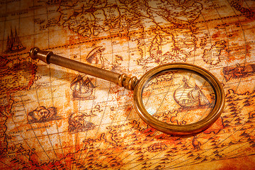 Image showing Vintage magnifying glass lies on an ancient world map