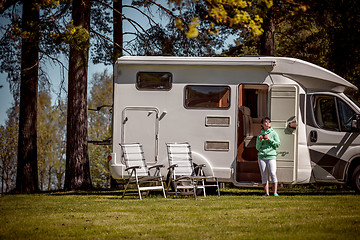 Image showing Woman is standing with a mug of coffee near the camper RV.