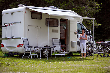 Image showing Woman is standing with a mug of coffee near the camper RV.