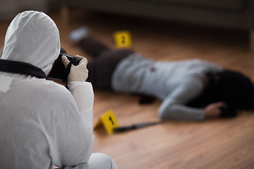 Image showing criminalist photographing dead body at crime scene