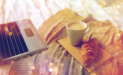 Image showing laptop, coffee and croissant on bed at cozy home