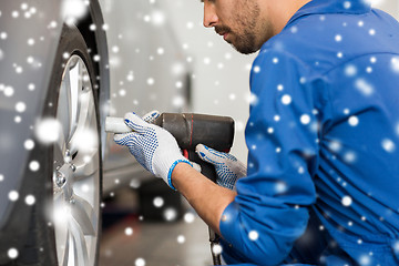 Image showing auto mechanic with screwdriver changing car tire