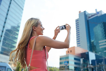 Image showing young woman with smartphone photographing city