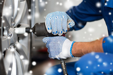 Image showing auto mechanic with screwdriver changing car tire