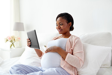 Image showing happy pregnant woman with tablet pc at home