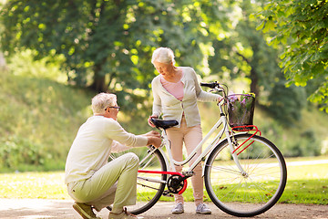 Image showing happy senior couple with bicycle at summer park