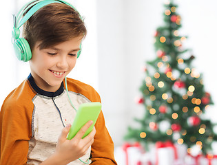 Image showing boy with smartphone and headphones at christmas