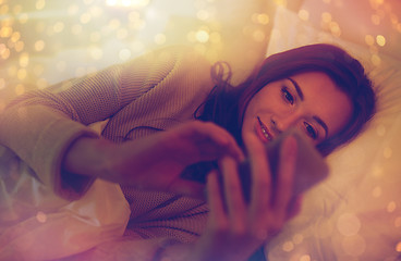 Image showing young woman with smartphone in bed at home bedroom