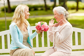 Image showing daughter giving flowers to senior mother at park