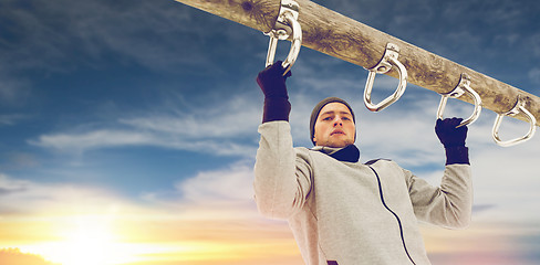 Image showing young man exercising on horizontal bar in winter